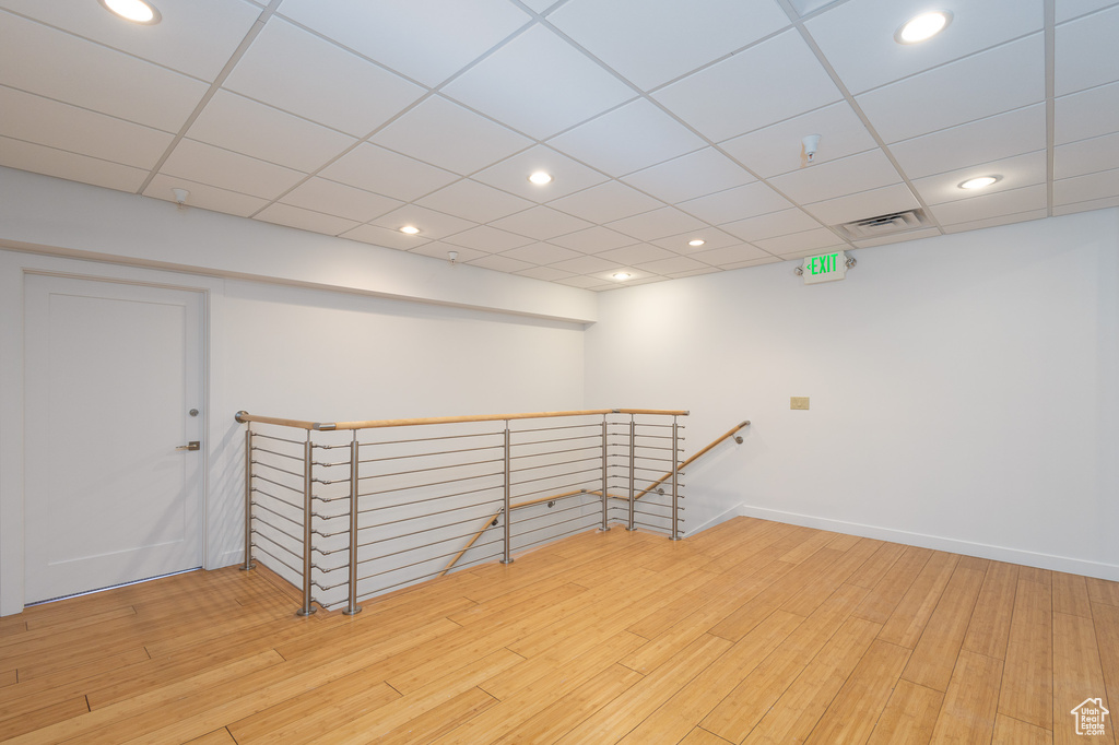 Spare room with a paneled ceiling and light wood-type flooring