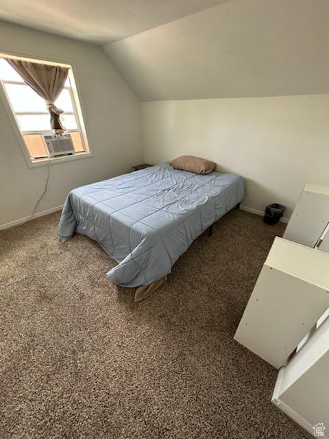 Bedroom with lofted ceiling, cooling unit, and carpet flooring