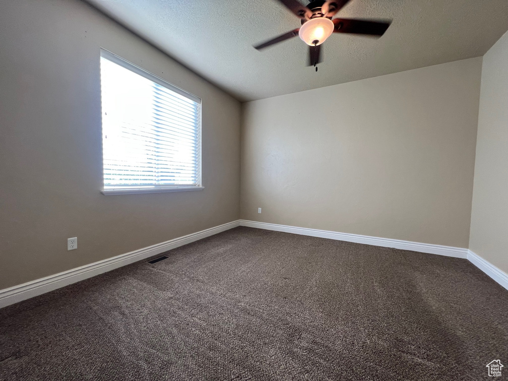 Unfurnished room featuring a textured ceiling, ceiling fan, and carpet