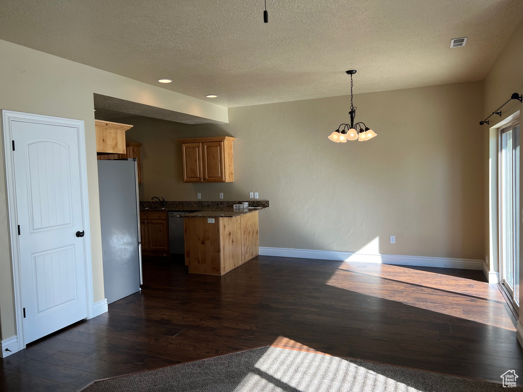 Kitchen featuring white refrigerator, a healthy amount of sunlight, kitchen peninsula, and dark hardwood / wood-style floors