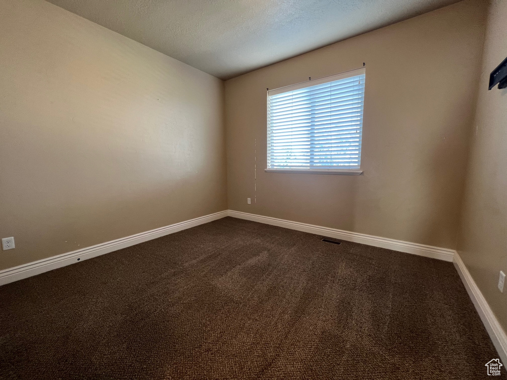 Carpeted spare room featuring a textured ceiling