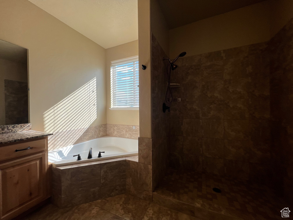 Bathroom with tile patterned flooring, vanity, vaulted ceiling, and plus walk in shower