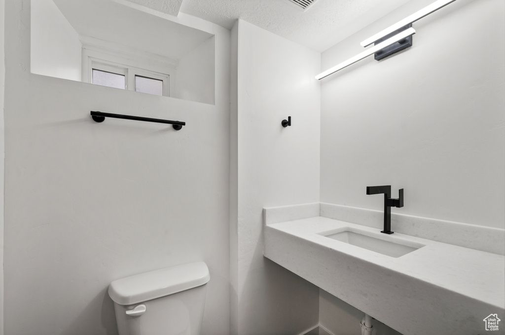 Bathroom with sink, toilet, and a textured ceiling