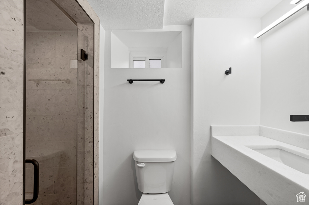 Bathroom featuring a textured ceiling, walk in shower, and toilet