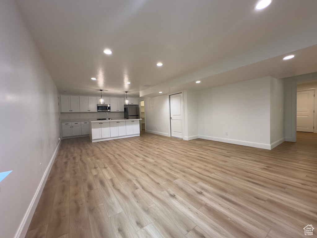 Unfurnished living room with recessed lighting, baseboards, and light wood-style floors