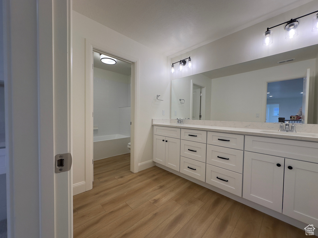 Bathroom with wood finished floors, double vanity, and baseboards