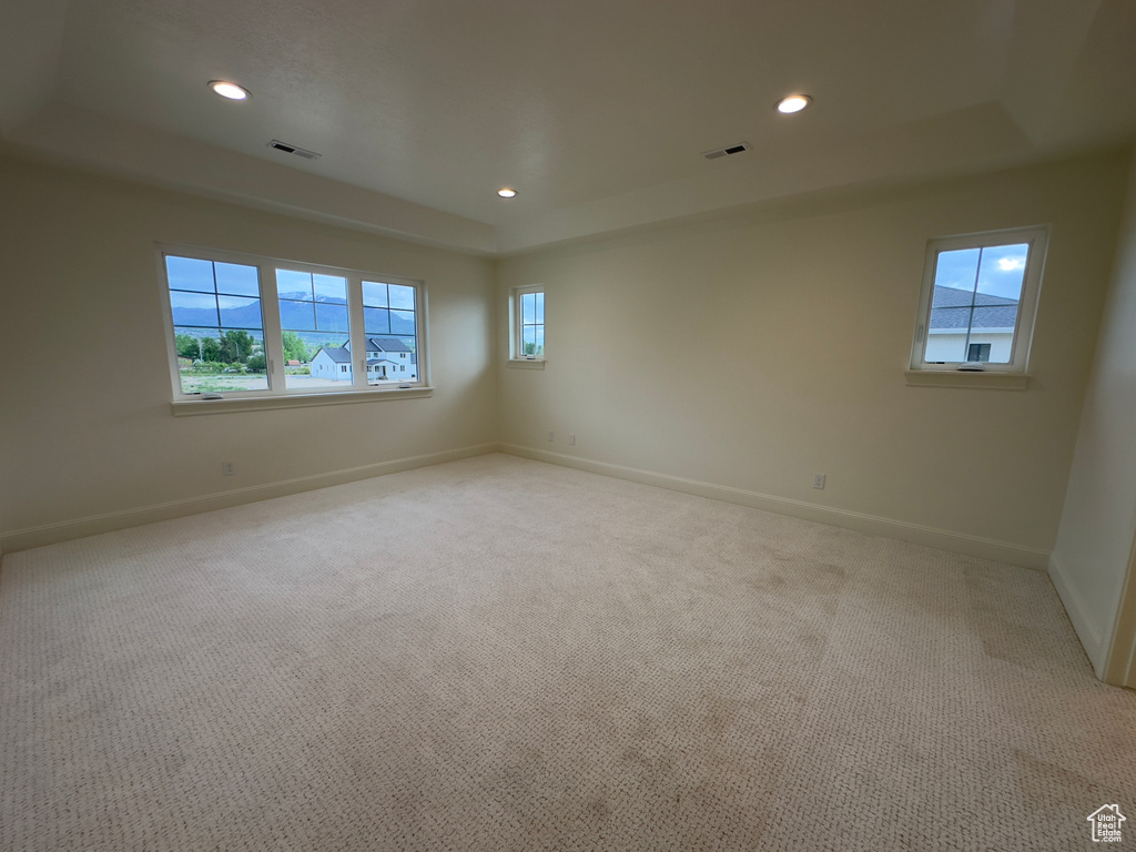 Unfurnished room with a raised ceiling, light carpet, and recessed lighting