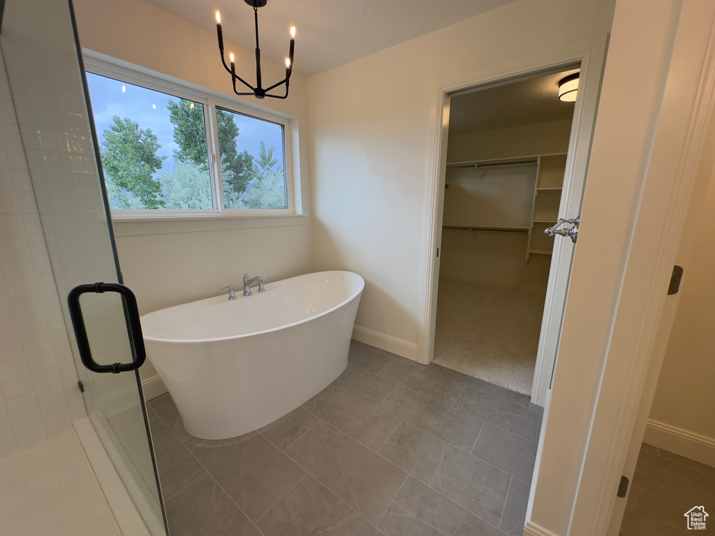 Bathroom with a spacious closet, a freestanding bath, a shower stall, a chandelier, and baseboards