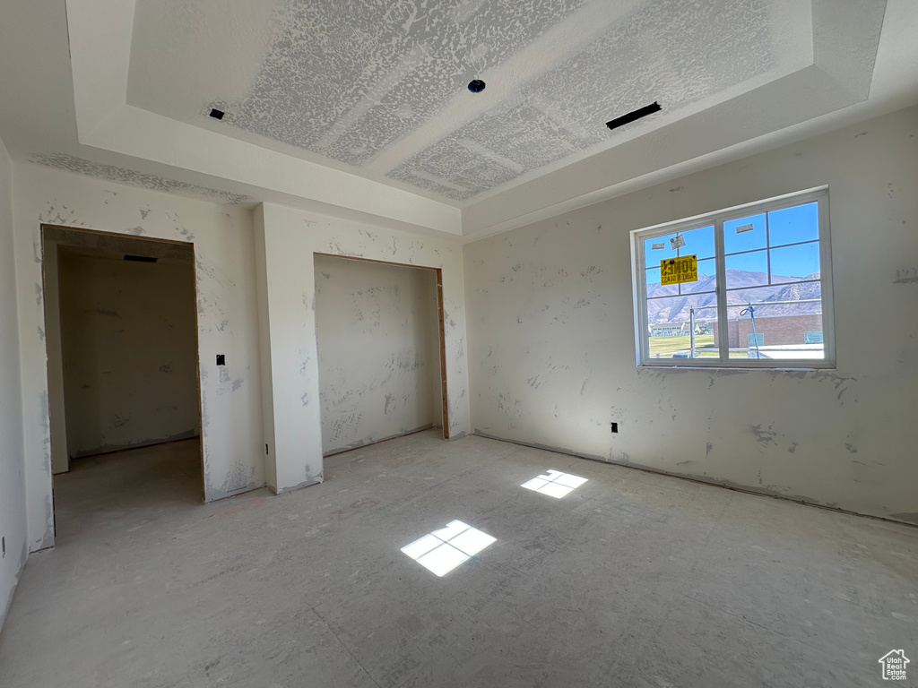 Unfurnished bedroom featuring a tray ceiling