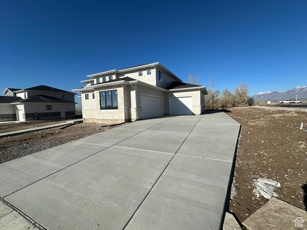 View of side of property with a mountain view and a garage