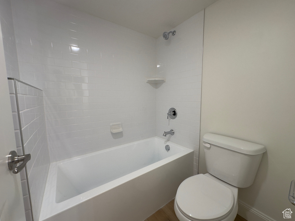 Full bath with toilet, bathtub / shower combination, baseboards, and wood finished floors