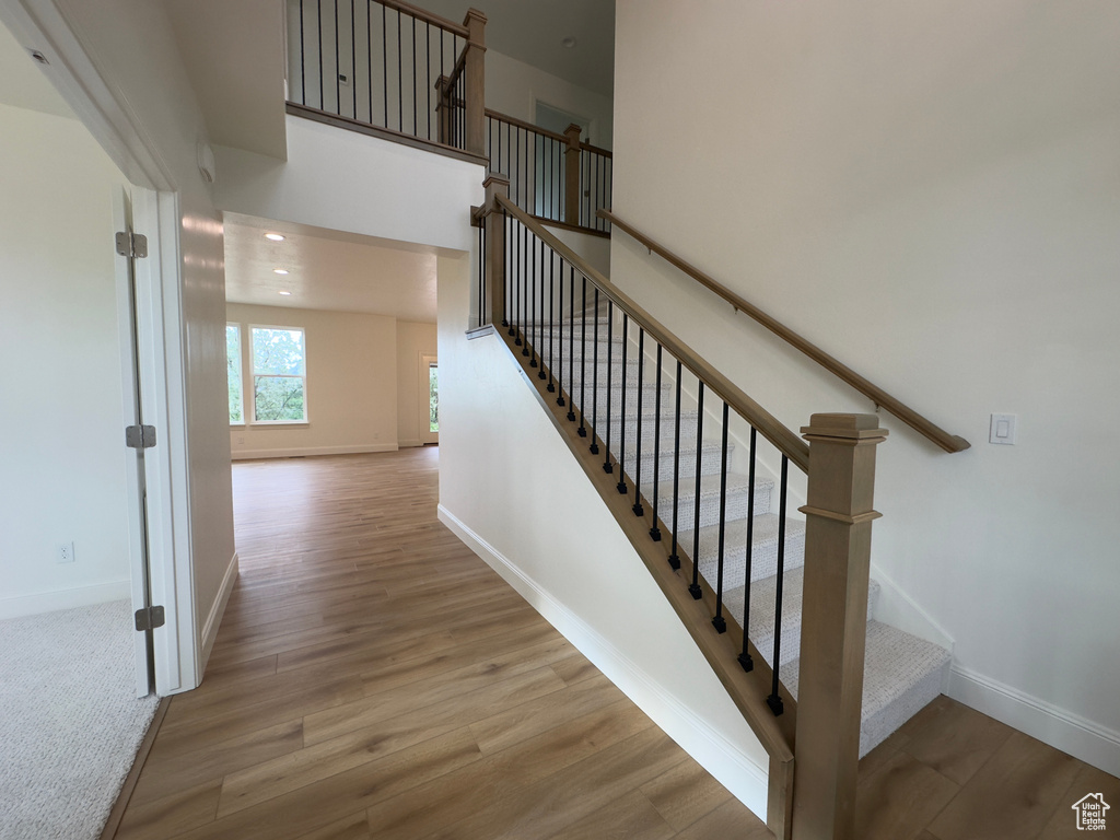 Staircase with baseboards, wood finished floors, and recessed lighting