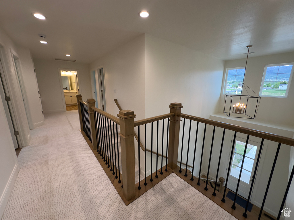 Hall with an upstairs landing, a chandelier, recessed lighting, light carpet, and baseboards
