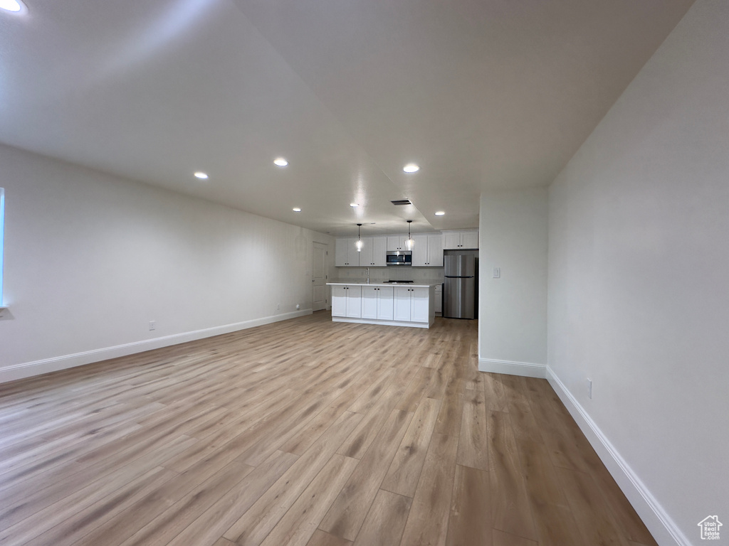 Unfurnished living room featuring recessed lighting, baseboards, and light wood-style floors