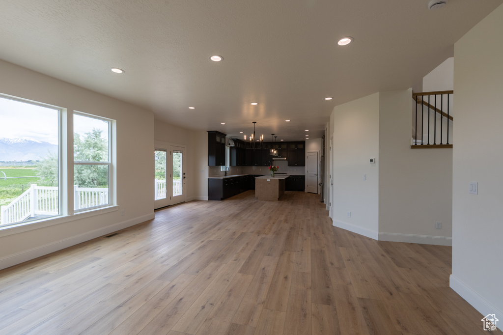 Unfurnished living room featuring a chandelier, light wood-type flooring, recessed lighting, and baseboards