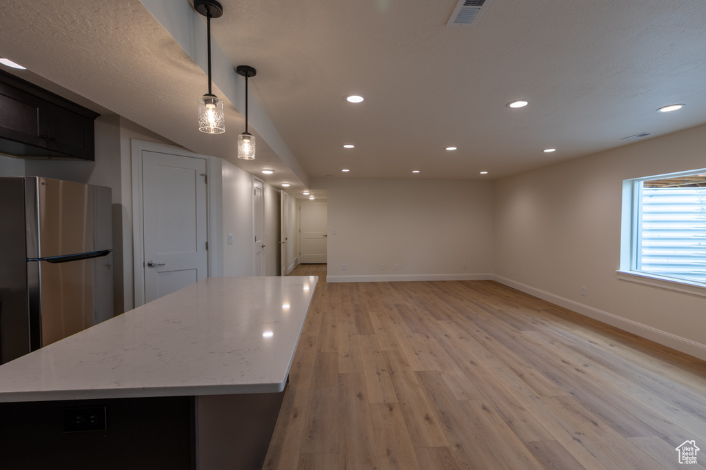 Kitchen featuring freestanding refrigerator, baseboards, light wood-style floors, a kitchen island, and recessed lighting