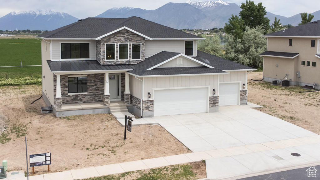 Craftsman-style house with stone siding, covered porch, a garage, and roof with shingles