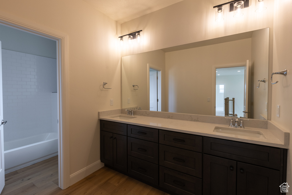Bathroom featuring wood finished floors, double vanity, and baseboards