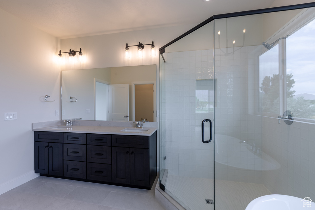 Full bathroom featuring a shower stall, double vanity, tile patterned flooring, and baseboards