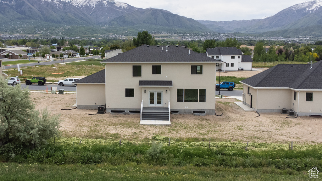 Back of house featuring a mountain view, french doors, central AC unit, and stucco siding