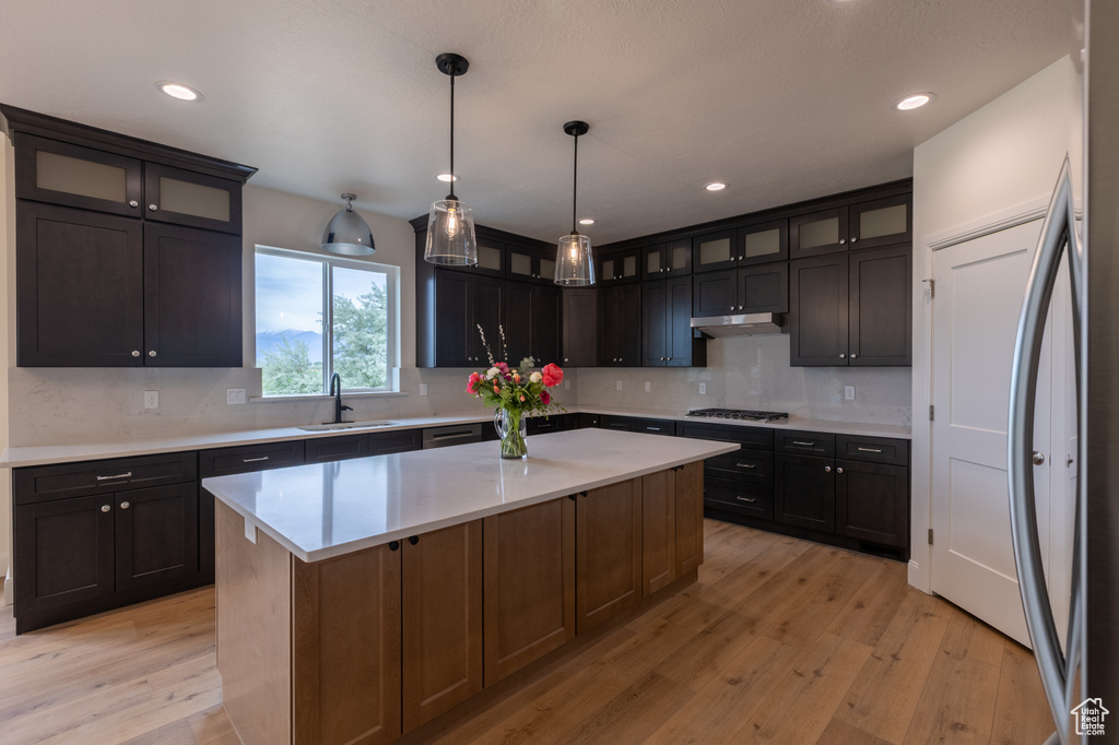 Kitchen with a sink, stainless steel fridge, light wood-type flooring, backsplash, and recessed lighting
