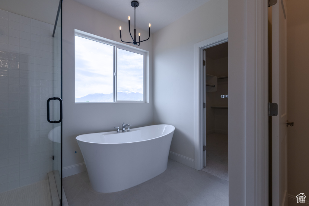 Bathroom featuring a shower stall, a freestanding bath, a chandelier, a spacious closet, and baseboards