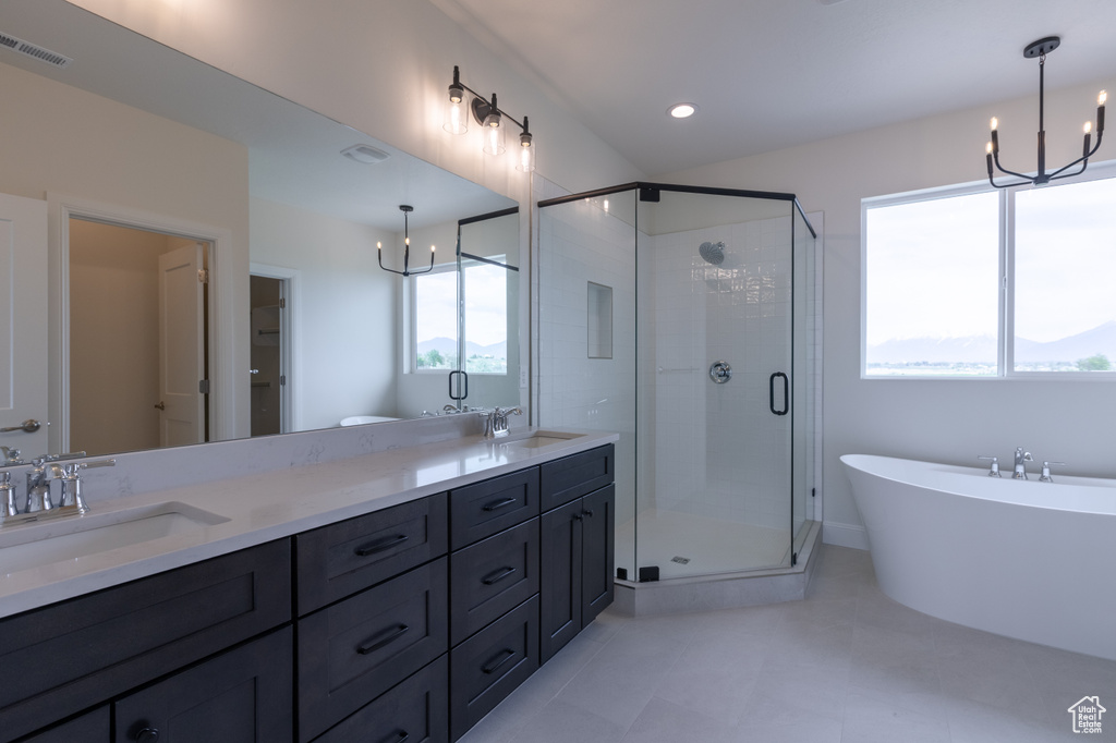 Full bathroom featuring a stall shower, a chandelier, double vanity, a freestanding tub, and tile patterned flooring