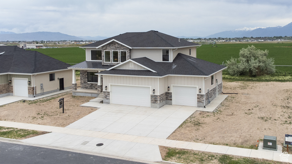 View of front of house with stone siding, a mountain view, board and batten siding, driveway, and a garage