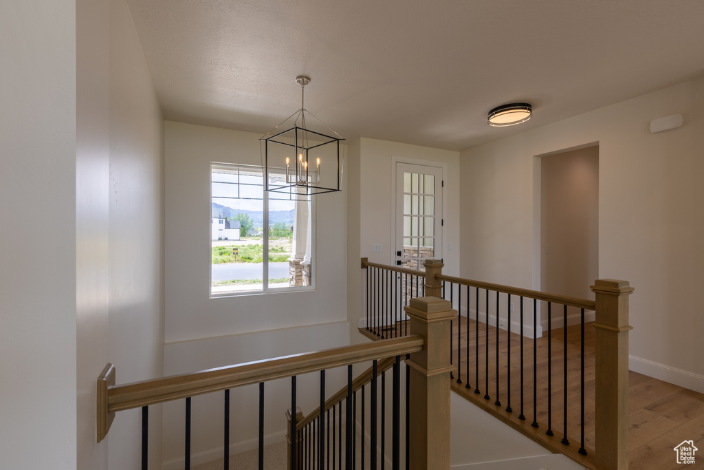 Staircase with a chandelier, wood finished floors, and baseboards