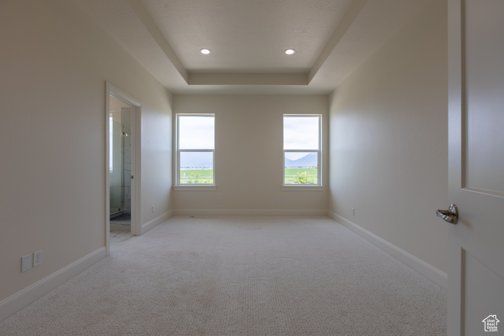 Unfurnished room with light carpet, recessed lighting, a tray ceiling, and baseboards