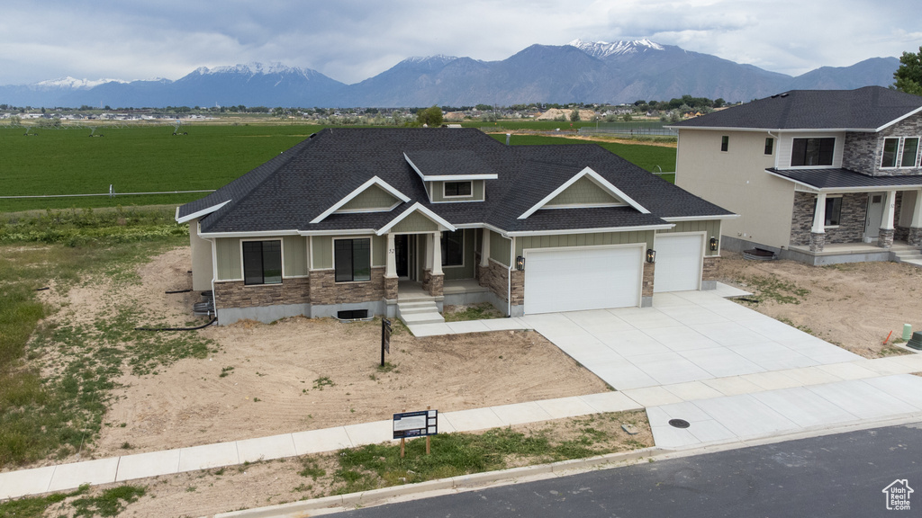 Craftsman-style home featuring a porch, an attached garage, concrete driveway, stone siding, and a mountain view