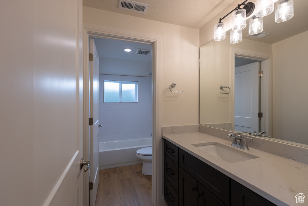 Bathroom with vanity, toilet, wood finished floors, and a bathtub