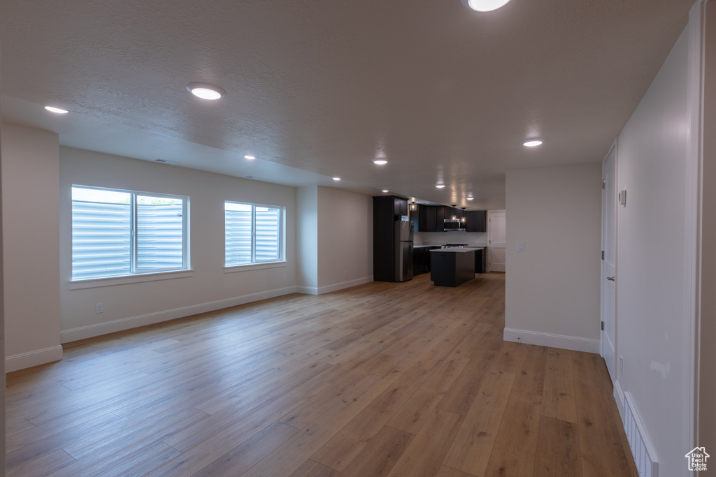 Unfurnished living room featuring recessed lighting, light wood-style floors, and baseboards