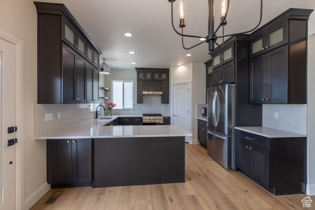 Kitchen with stainless steel appliances, a sink, a peninsula, light wood-type flooring, and recessed lighting