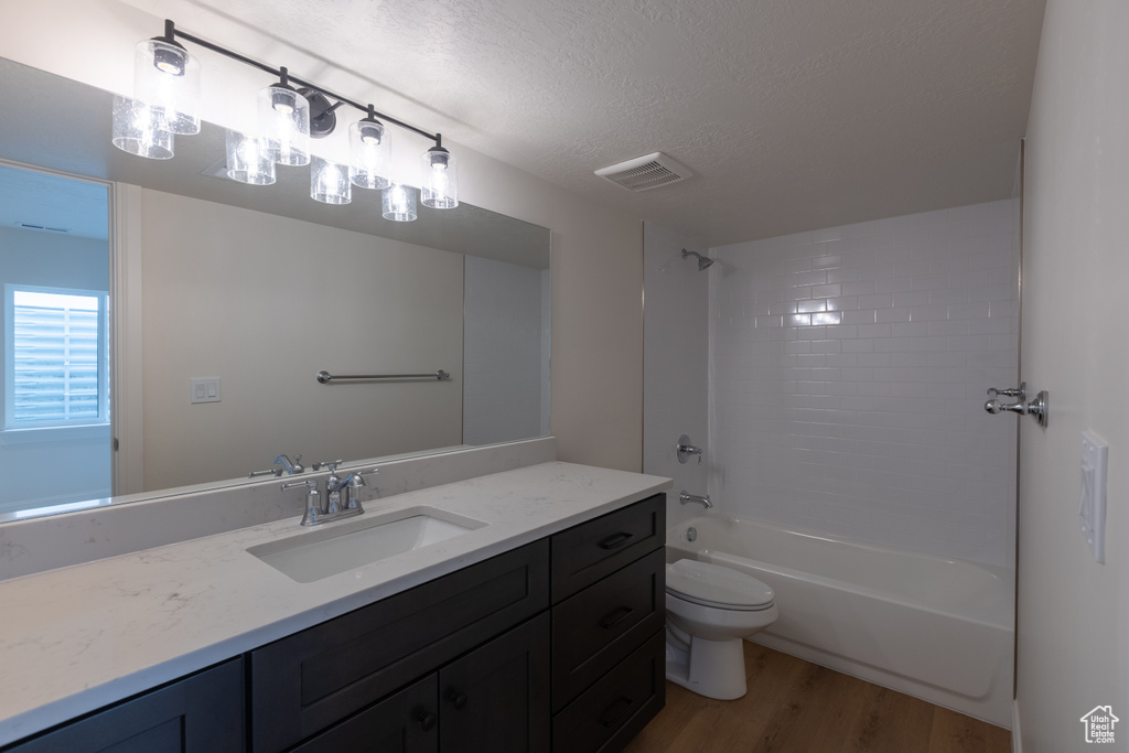 Full bathroom with wood finished floors, a textured ceiling, vanity, toilet, and shower / tub combination