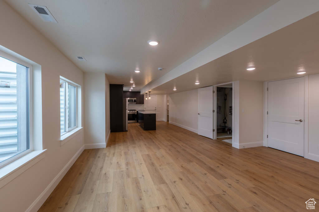 Unfurnished living room featuring light wood-type flooring, baseboards, and recessed lighting