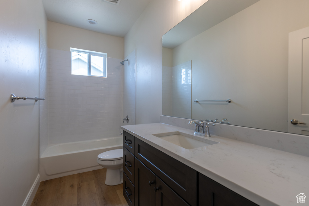 Full bath with toilet, vanity, wood finished floors, and tub / shower combination