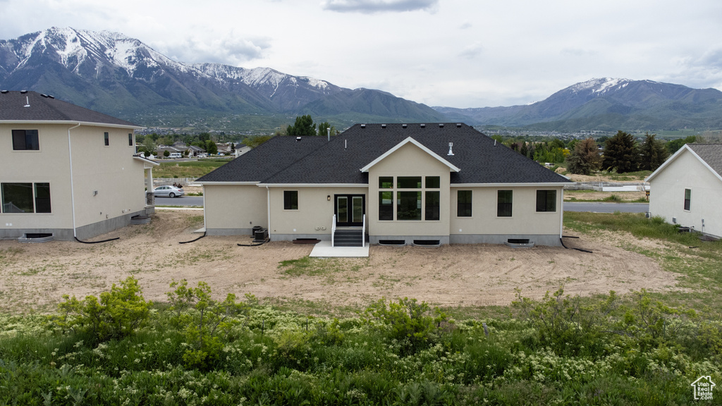 Back of property featuring a mountain view and a shingled roof