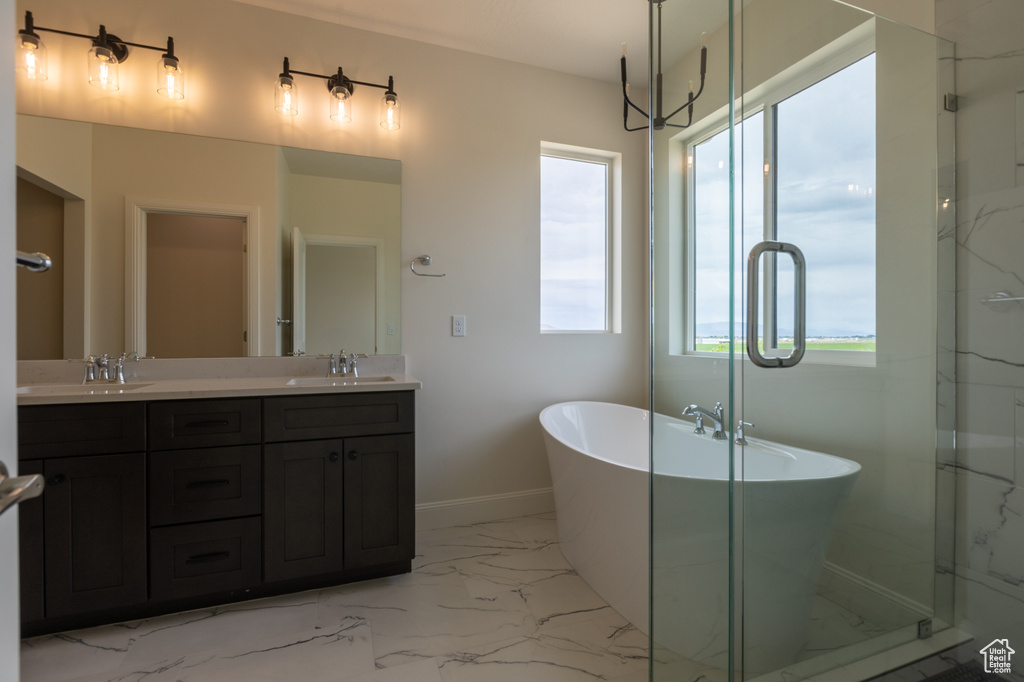 Bathroom featuring marble finish flooring, double vanity, a freestanding bath, a marble finish shower, and baseboards