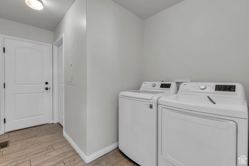 Laundry area featuring washing machine and clothes dryer and light hardwood / wood-style flooring