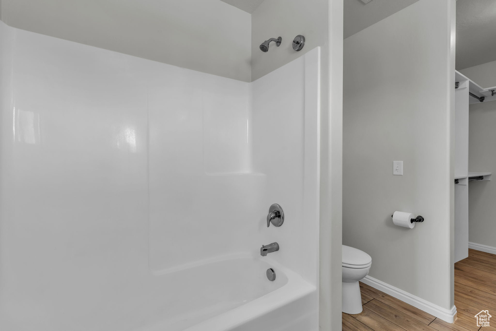 Bathroom featuring hardwood / wood-style floors,  shower combination, and toilet