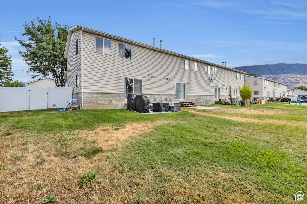 Back of house featuring a lawn, a mountain view, and central AC