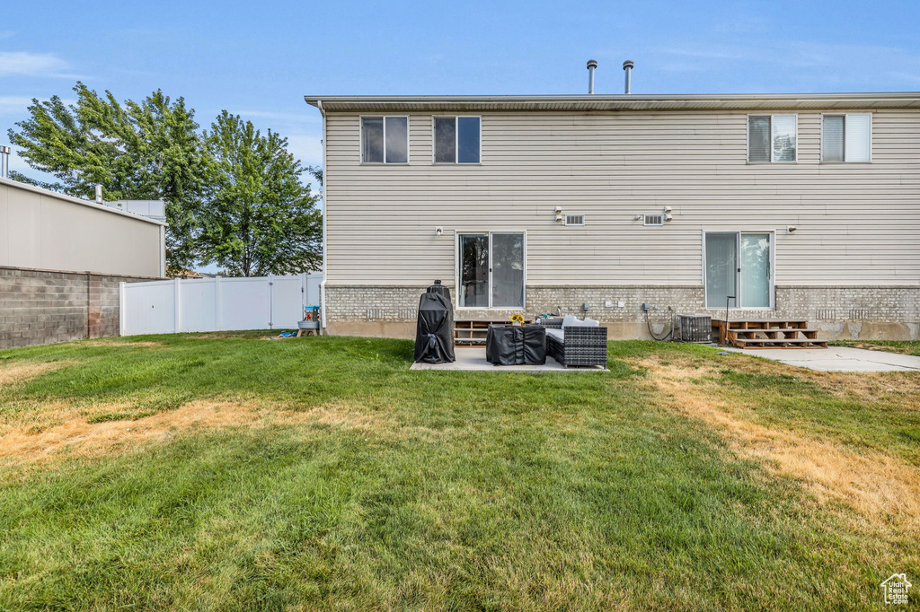 Back of house featuring central AC unit, a patio, and a lawn