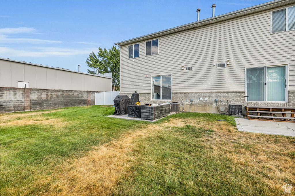 Back of property featuring cooling unit, a patio area, and a yard