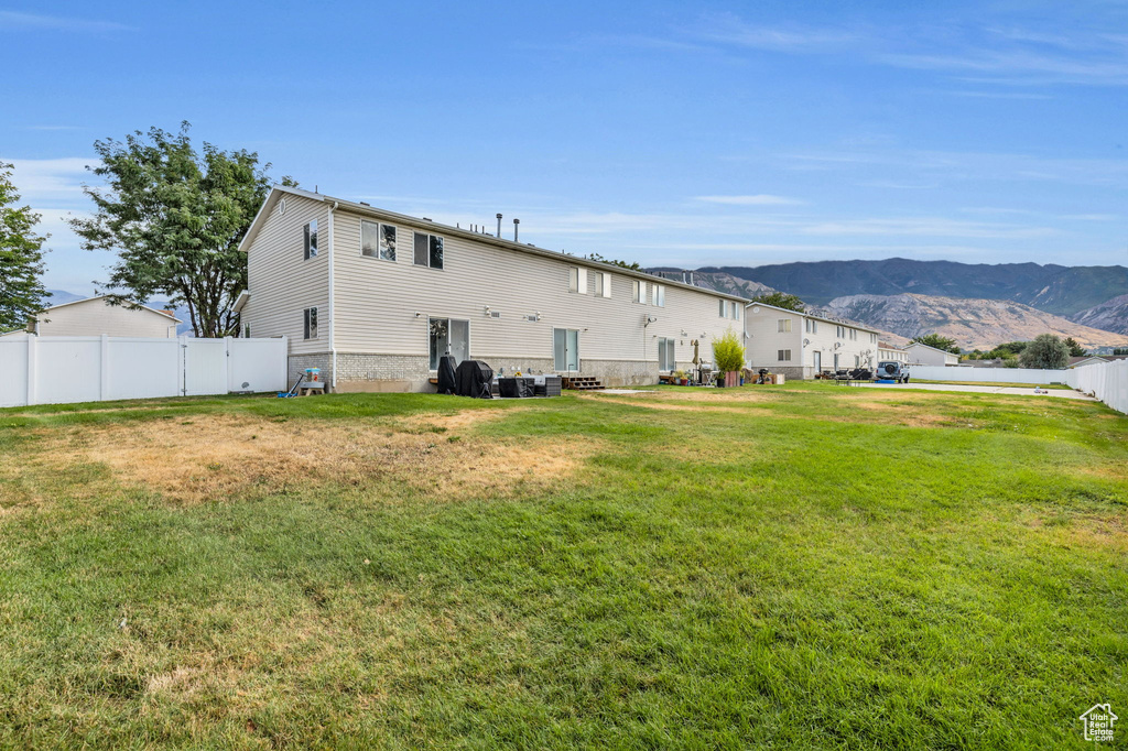 Rear view of house featuring a mountain view and a yard