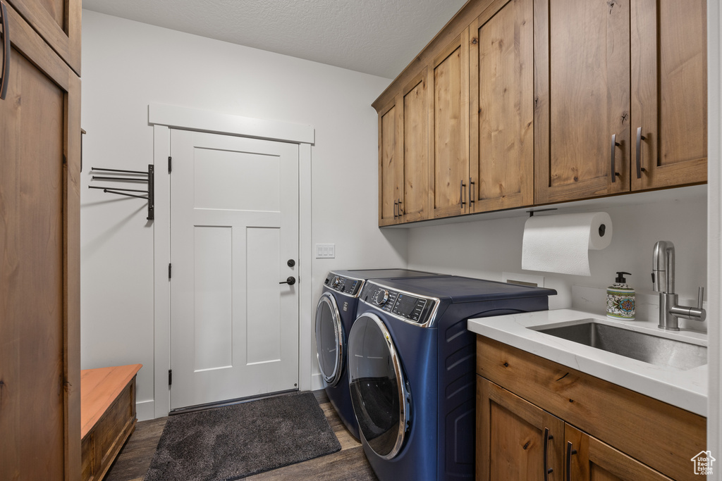 Laundry area featuring sink, washing machine and clothes dryer, cabinets, and dark hardwood / wood-style floors