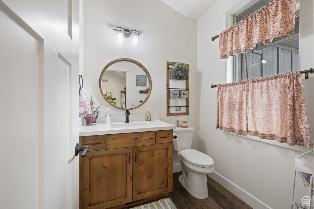 Bathroom featuring wood-type flooring, toilet, and vanity