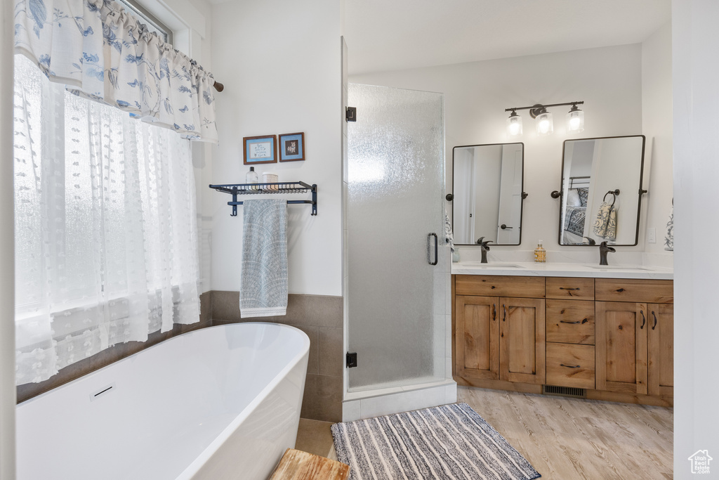 Bathroom featuring tile walls, double vanity, independent shower and bath, and wood-type flooring