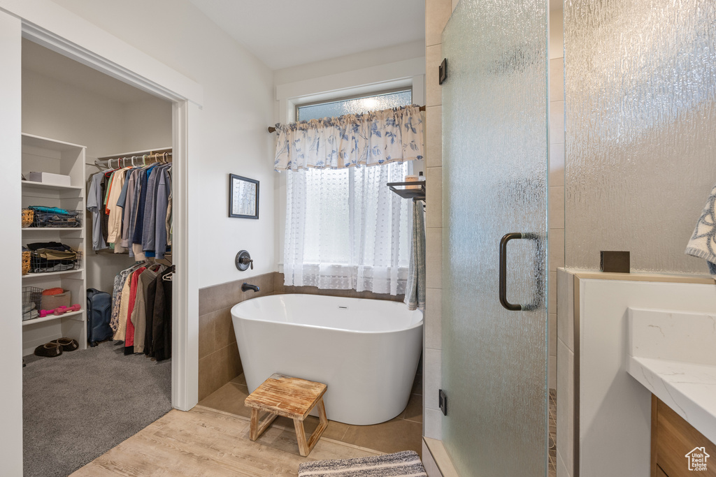 Bathroom featuring wood-type flooring, a tub to relax in, and tile walls