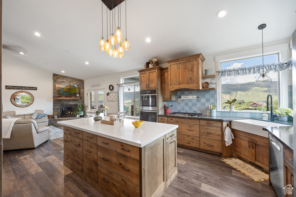 Kitchen featuring dark hardwood / wood-style flooring, backsplash, lofted ceiling, and a stone fireplace